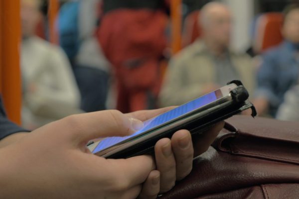 Close-up shot of a woman commuter browsing web on smart phone during ride in subway train